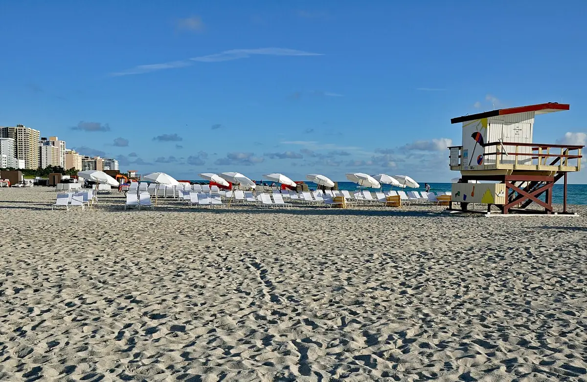 Plage de South Beach : sable blanc, parasols et tour de sauveteur colorée sous le ciel bleu